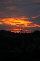 A dramatic sunset sky with colourful glowing clouds and a silhouetted landscape below
