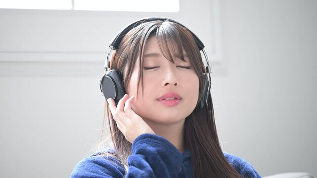 ヘッドフォンをつけて音楽を聴く歌う若い女性のクローズアップイメージの動画