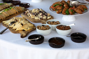 Catering buffet table displaying cheese, nuts, jams, and croissants with spoons and servers