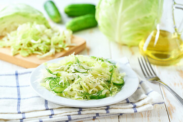 Fresh vegetable salad of of cabbage, cucumber and dill on a wooden table. Healthy food.