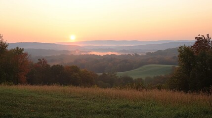 Obraz premium A scenic view of a valley with rolling hills and a sunrise casting a warm glow on the landscape.