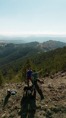 A young couple of travelers are staying on Tornik Mountain with two happy dogs and smiling, waving their hands. Aerial view from a drone. Beautiful nature of Western Serbia in early autumn.
