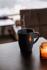 cup of tea and a candle on a wooden board in the background.