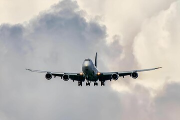 Jet airliner is descending towards an airport. The plane is flying through a cloudy sky.