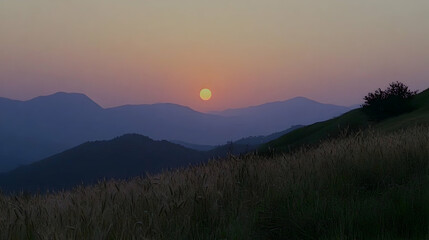 Fototapeta premium A scenic sunset over rolling hills with a golden sun setting behind the mountains.