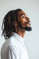 Obraz premium Side profile of a man with dreadlocks, stark white background, minimalist lighting