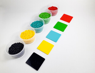 Various colors of masterbatch granules in a cup equipped with color chips as examples of the resulting colors, isolated on a white background. Polymers carrying color pigments in the plastics industry