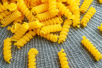 Spiral fusilli pasta spread on a textured mat. Raw ingredients for traditional Italian cuisine....