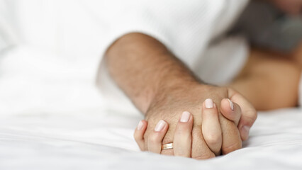 Sensual couple in bed enjoying privacy with each other. Focus on the hands of the man and woman.