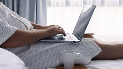 A middle-aged man works remotely on his laptop, focused and productive. This scene captures the essence of freelance life, blending professionalism with the comforts of home.