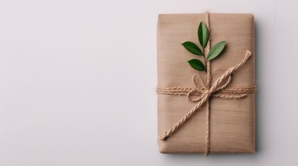 A beautifully wrapped gift in natural burlap, tied with twine and adorned with a small green leaf, ideal for eco-friendly gifting.