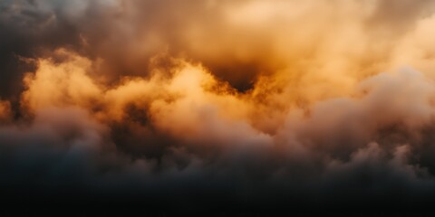 Obraz premium Dramatic clouds illuminated by sunset hues in fiery mix of orange and gold