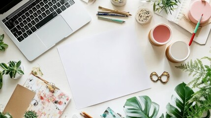 A workspace with a laptop, stationery, and plants, ready for creative tasks.