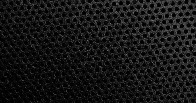 Black Perforated Surface Texture. Close-up view of a black perforated surface with a repeating hole pattern, creating a textured and industrial look.
