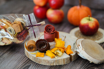 Freshly rolled, homemade fruit leather and dried fruit slices made from organic ingredients are displayed on a rustic table