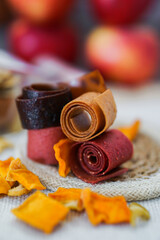 Freshly rolled, homemade fruit leather and dried fruit slices made from organic ingredients are displayed on a rustic table