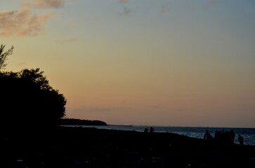 Golden hour hues paint the coastal scene, casting long shadows across the tranquil shore
