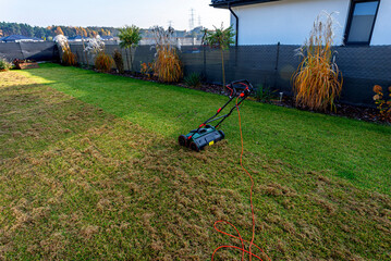 Scarifying the lawn before the winter season using an electric scarifier.