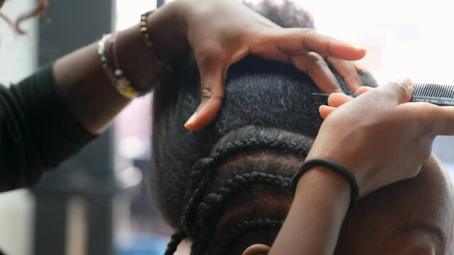 Hairdresser using a comb to separate the hair to make crochet braids to a client in an afro hair salon