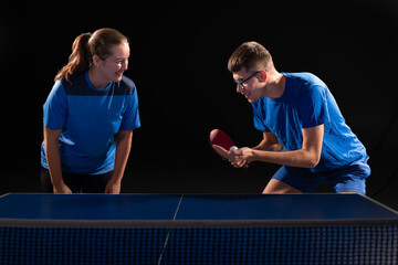 A guy and a girl are playing table tennis together against opponents.