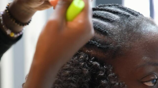 Hairdresser making individual crochet braids in an afro hair salon using a crochet needle
