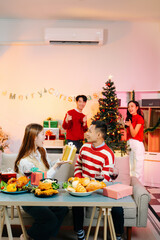 Asian friends capture the holiday spirit with gifts, laughter, and a festive Christmas dinner in a cozy, joy-filled setting