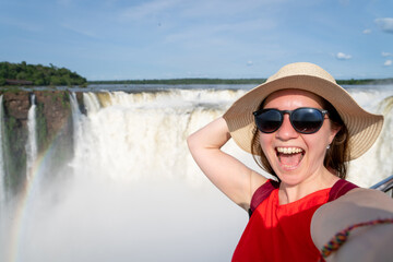 Turista feliz tomándose una selfie en el Parque Nacional Iguazú, con las cataratas de fondo