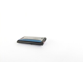 An old cell phone battery that is bloated and damaged on a white background