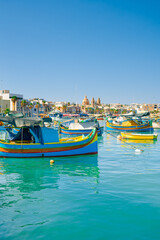 Obraz premium Traditional colorful fishing boats Luzzu in the Harbor of Mediterranean fishing village Marsaxlokk at sunny day, Malta.