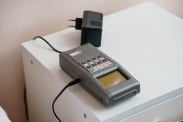Analog Multimeter and Charger on a White Nightstand