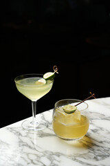 Two cocktails in classic martini and whiskey glass with feijoa on a bar counter, close-up
