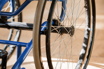 Detailed Close-Up of a Blue Wheelchair Wheel with Spokes in a Softly Lit Environment