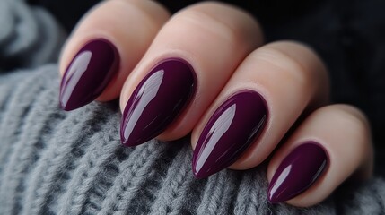 Stylish deep purple manicure on elegantly shaped nails in cozy setting