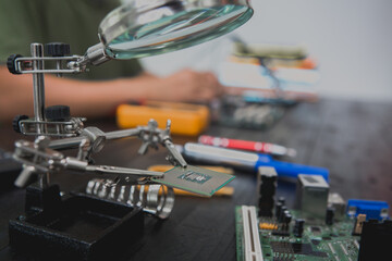Asian male computer repairman is checking and fixing hardware problems on computers and replacing...