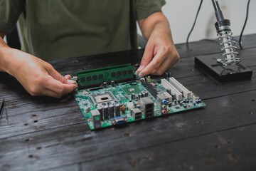 Asian male computer repairman is checking and fixing hardware problems on computers and replacing...
