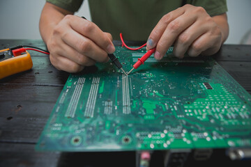 Asian male computer repairman is checking and fixing hardware problems on computers and replacing...