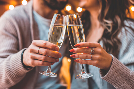 Romantic Valentine's Day Toast with Champagne. Close-up of hands holding champagne flutes during a romantic celebration. The warm bokeh lights create an intimate atmosphere.