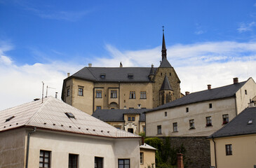 Obraz premium Photo of a castle on a hill in a part of town. A castle on top of a hill. Below the castle, houses and buildings of the castle complex. Monument, travel, tourist spot, fantasy, fairy tale.