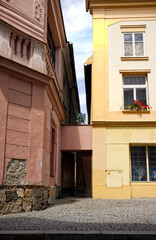 Naklejka premium Houses in the street. Colorful facades of houses connected by wooden gates. Ornamental decorative facades. Paved sidewalk on the street. Narrow alley between houses.