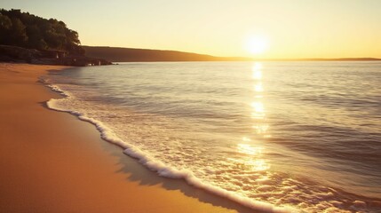 Obraz premium As the sun sets on the horizon, warm golden hues illuminate the tranquil waves gently lapping the sandy shore. The peaceful ambiance invites a moment of serene reflection.