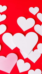 white pink paper hearts scattered on a red surface