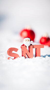 festive red figure stands before the letters 'snt' the snow