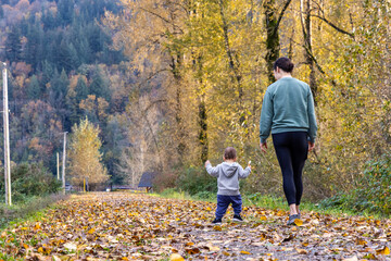 Fototapeta premium Mother and Child Walking in Autumn Forest Path
