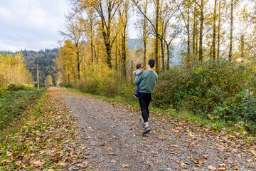 Mother and Child Walking on Autumn Path in Forest