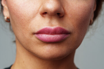 woman showcasing her natural skin texture and subtle lip color in soft lighting