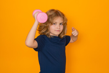 Portrait of sporty child with dumbbells, isolated on yellow studio background. Cute little boy doing exercises with dumbbells.