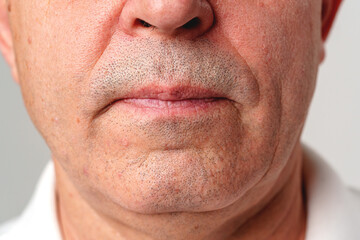 Obraz premium View of an older man's chin and mouth area against a neutral background