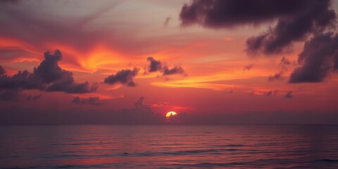 Vibrant orange and pink hues illuminate the sky as the sun dips below the horizon over a tranquil ocean scene, evening, serenity