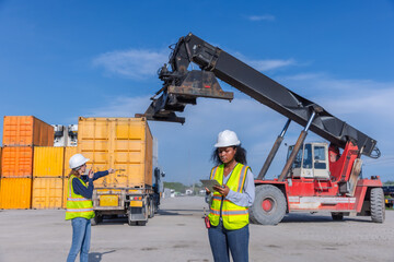 Workers in a shipping yard coordinating the unloading of cargo containers using a large crane,...