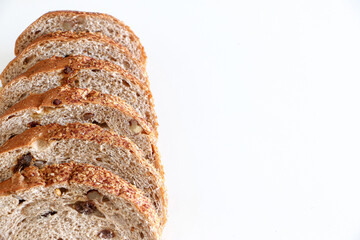 Close up of the texture of 6 slices of healthy whole grain raisin and walnut brown bread on left hand side of white background, copy space on right, healthy eating and lifestyle balanced diet concept